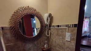 Ein Badezimmer mit Waschbecken, Fön und Spiegel mit dekorativem Rahmen.