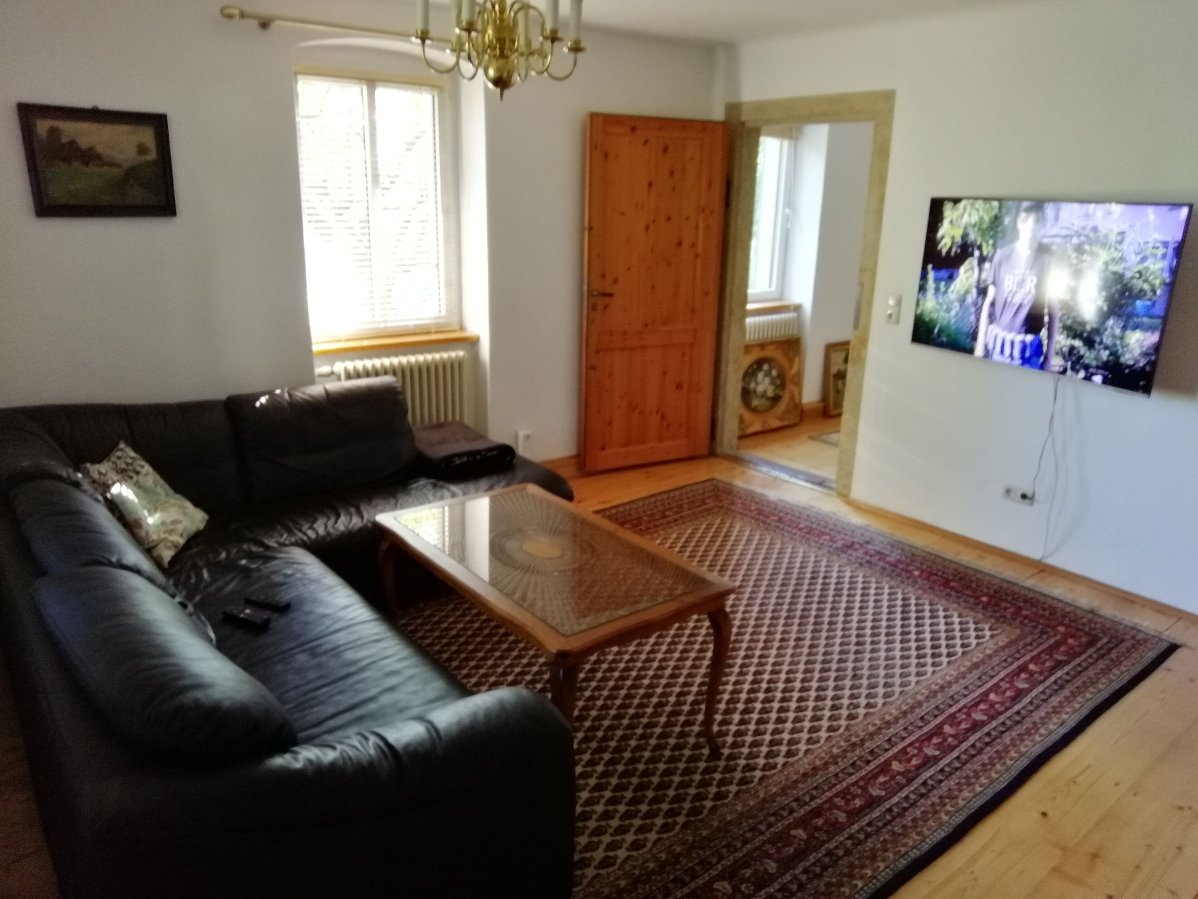 A living room with a black leather sofa, a wooden coffee table, and a patterned rug.