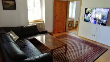 A living room with a black leather sofa, a wooden coffee table, and a patterned rug.