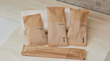 Three brown paper bags labeled "Cotton Set," "Razor," and "Hair Brush" on a white countertop.