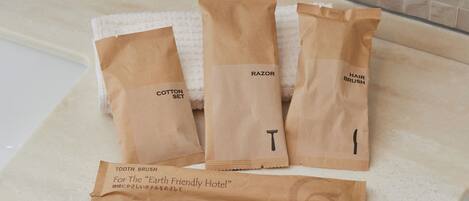 Three brown paper bags labeled "Cotton Set," "Razor," and "Hair Brush" on a white countertop.