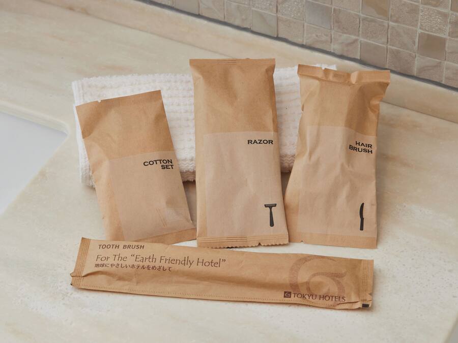 Three brown paper bags labeled "Cotton Set," "Razor," and "Hair Brush" on a white countertop.