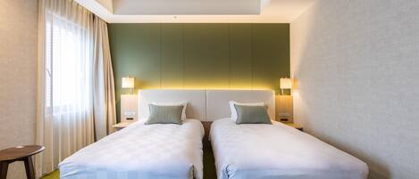 Habitación de hotel con dos camas individuales, una mesita y una silla.