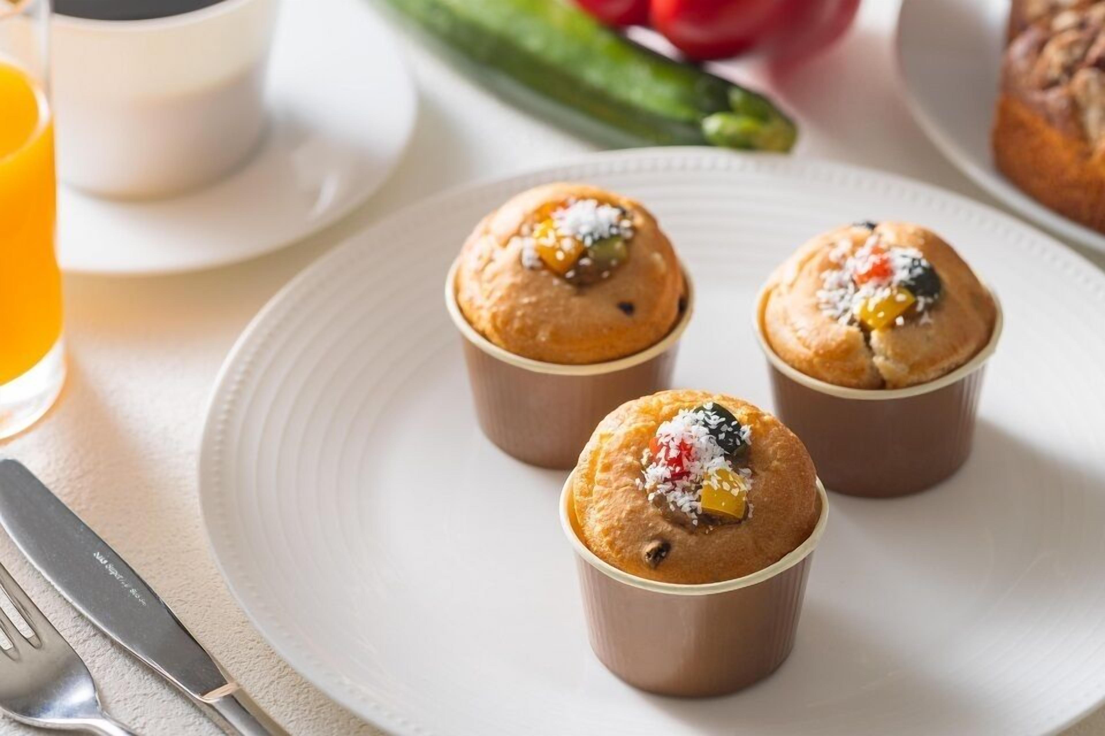 Tres muffins en un plato con un tenedor y un cuchillo cerca.