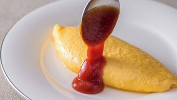 A plate with a folded omelette and a spoonful of ketchup.