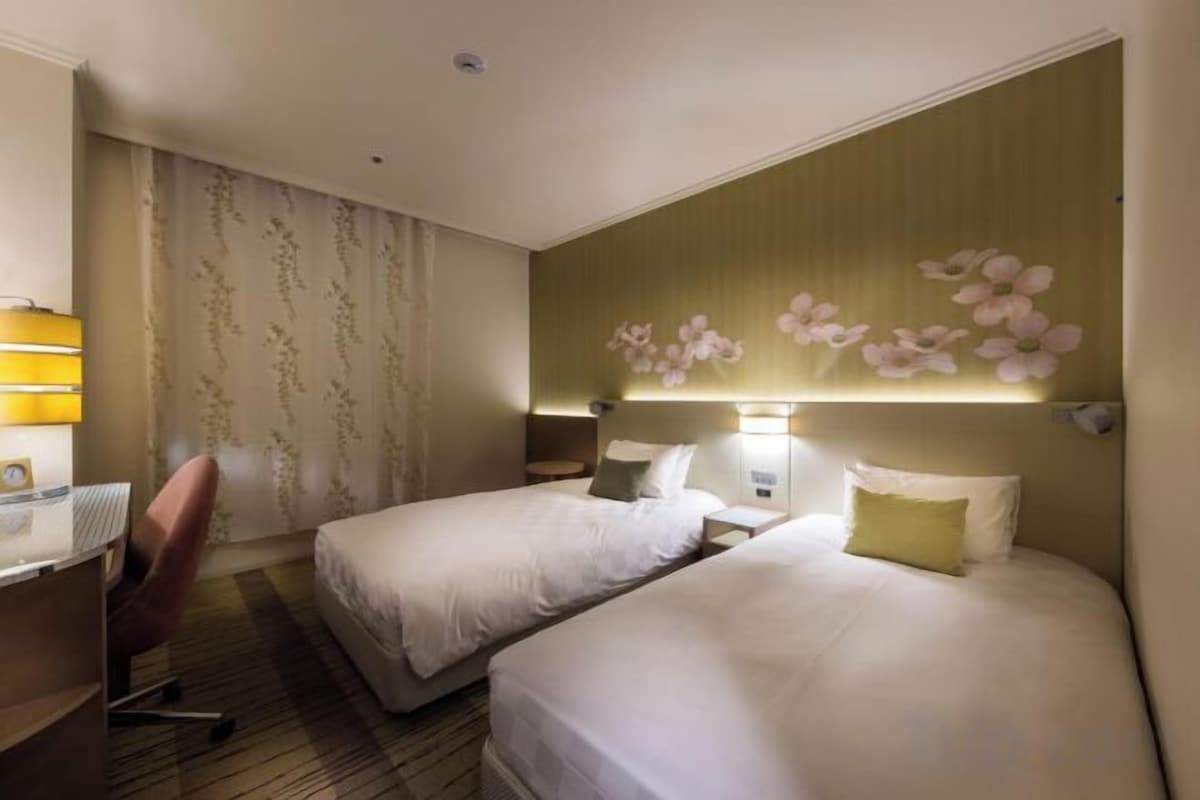 Een hotelkamer met twee bedden, een bureau en een stoel.