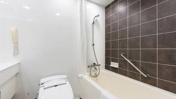 A bathroom with a white toilet, a bathtub with a showerhead, and a telephone on the wall.