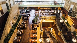 Un restaurante espacioso, de varios niveles, con diferentes opciones de asientos, incluyendo mesas y bancos, y una escalera central.