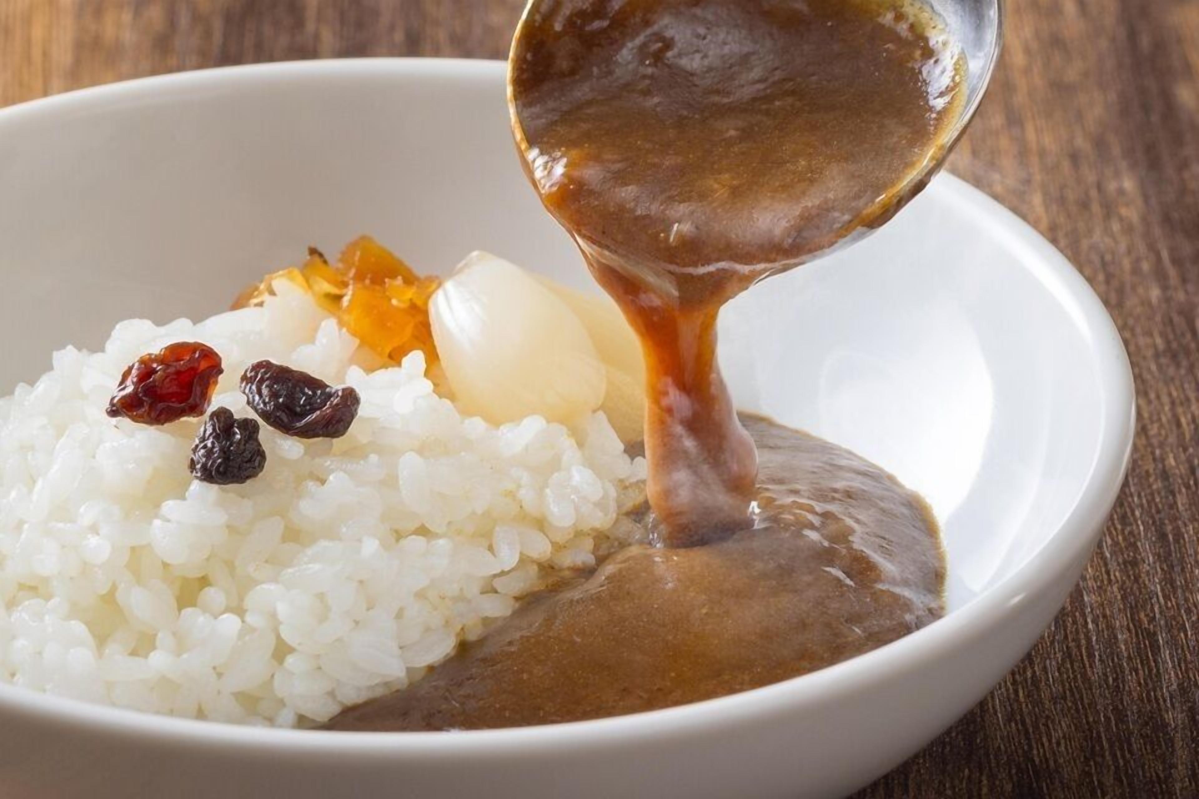 Una ciotola di riso bianco con salsa marrone, accompagnata da frutta secca.