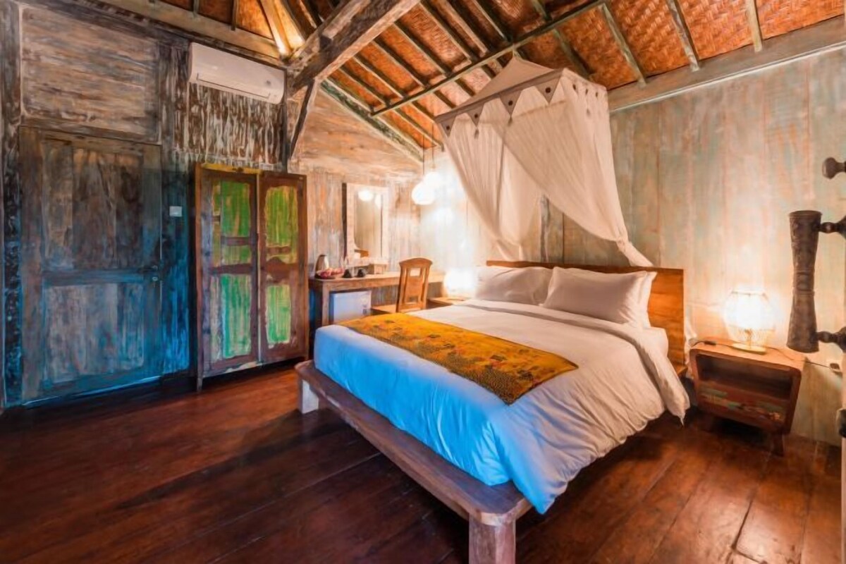 Una habitación rústica de madera con una cama, una mesita de noche y una silla.