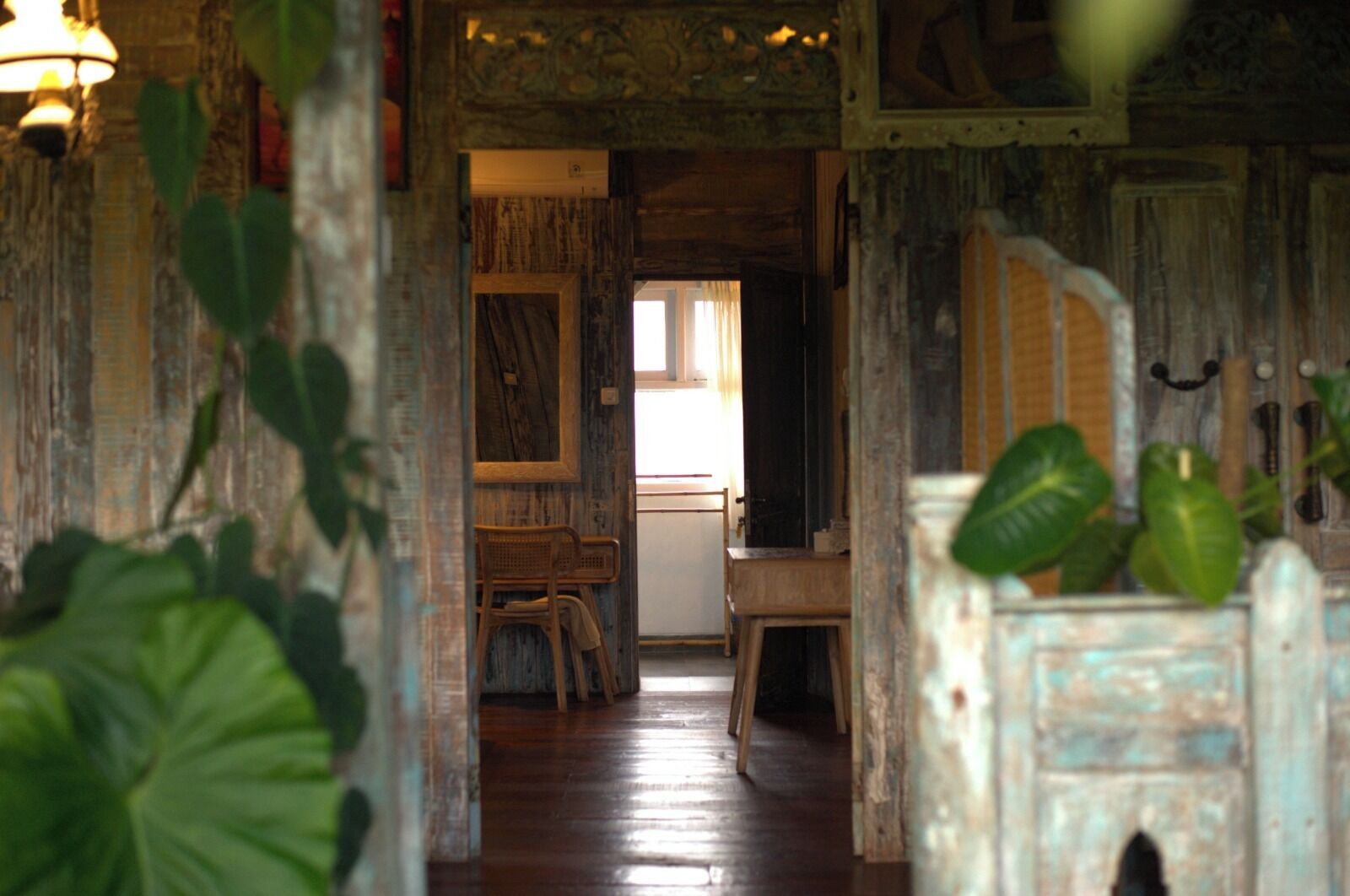 A rustic interior with wooden walls, a wooden floor, and a dining area with chairs and a table.