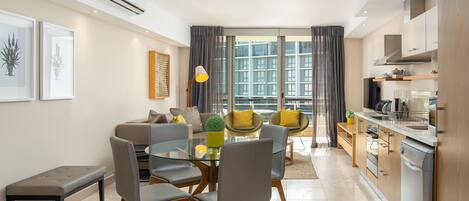A modern living room with a glass dining table, grey chairs, a sofa, and a coffee table.