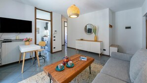A modern living room with a wooden coffee table, a grey sofa, a TV mounted on the wall, and a white cabinet. - The Rock View With Balcony and Parking (Arco)
