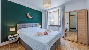 A bedroom with a large bed, a nightstand, a mirror, and a wardrobe. - The Rock View With Balcony and Parking (Arco)