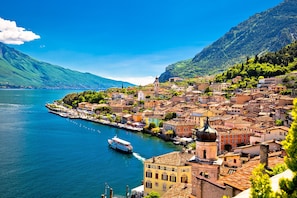 A coastal town with a prominent church tower, a waterfront promenade, and a boat docked near the shore.