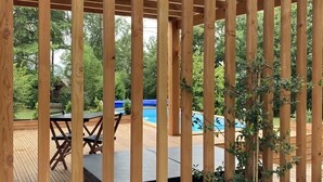 A wooden deck with a pool, surrounded by greenery.