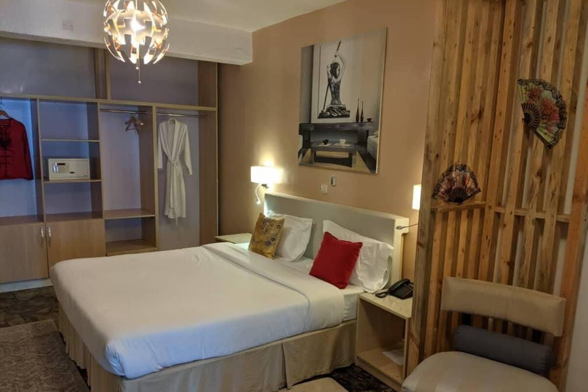 Un dormitorio con cama, mesita de noche, lámpara y cabecero de madera.