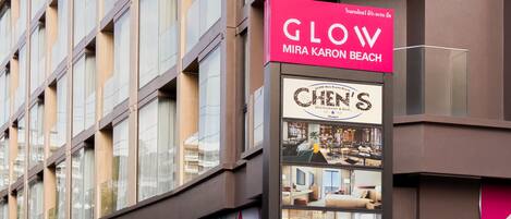 A building with a sign for 'GLOW Mira Karon Beach' and a 'Chen's Restaurant & Bar' sign.