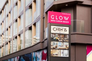En byggnad med en skylt som visar texten ”GLOW Mira Karon Beach” och en annan skylt som visar texten ”Chen’s Restaurant & Bar”.
