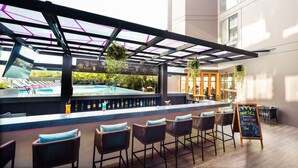 A bar area with a pool view, bar stools, and a chalkboard menu. - GLOW Mira Karon Beach (Karon)