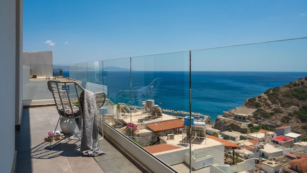 Een balkon met een helder uitzicht op zee, een stoel en een tafeltje.