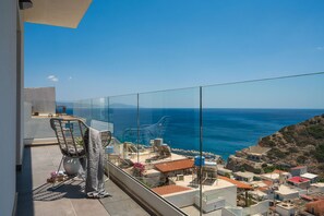 Un balcón con vista despejada al mar, una silla y una pequeña mesa.