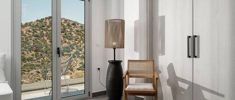 A modern room with a sliding glass door leading to a balcony, a tall floor lamp, a wooden chair, and a wardrobe.