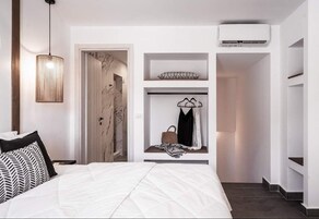 Une chambre moderne comprenant un lit, un luminaire suspendu, une armoire et un système de climatisation intégré.