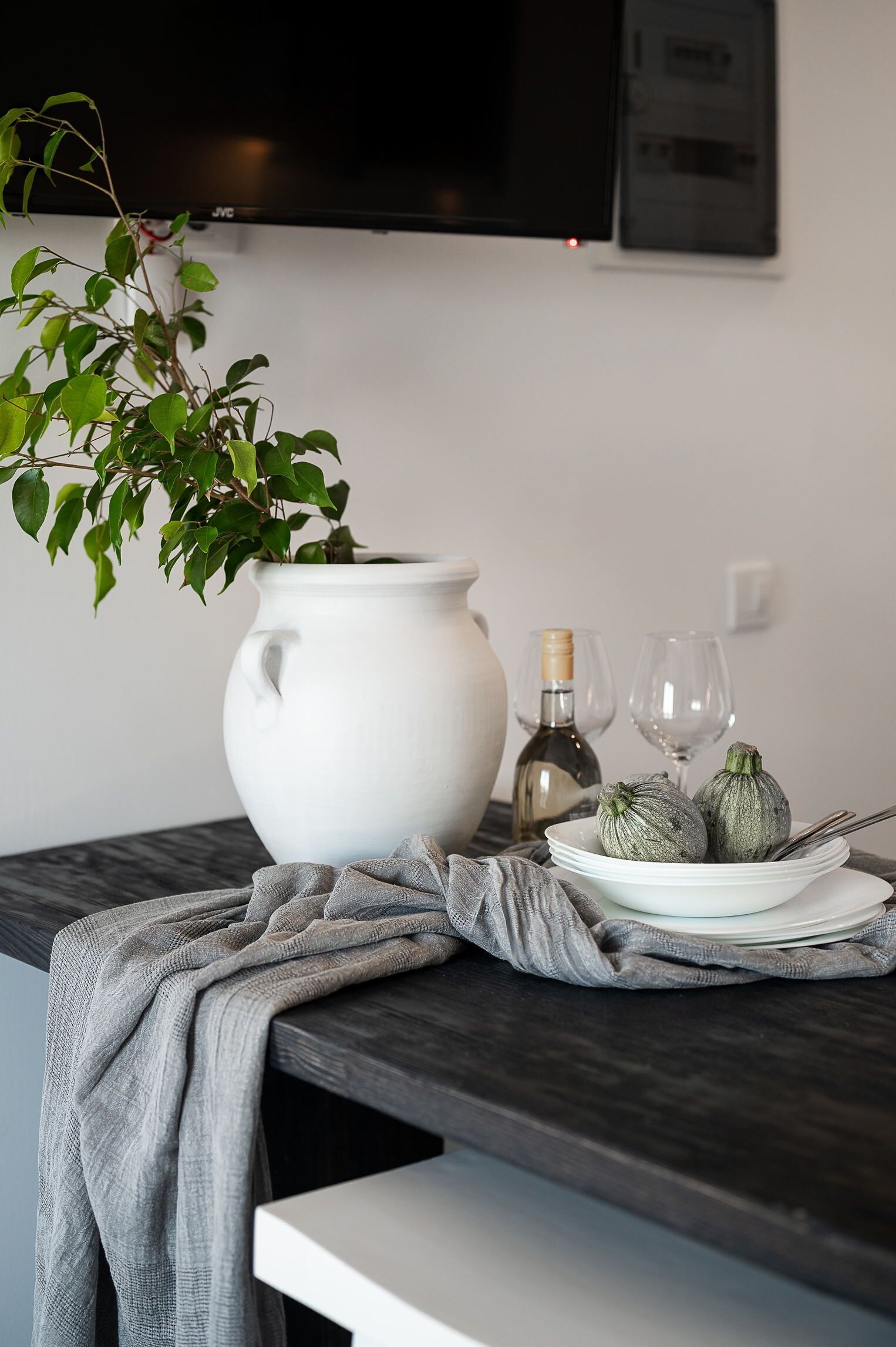 A modern kitchen with a white pot, a bottle, and two glasses on a marble countertop.