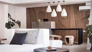 Een moderne woonkamer met een witte bank, een ronde salontafel en een houten accentmuur.