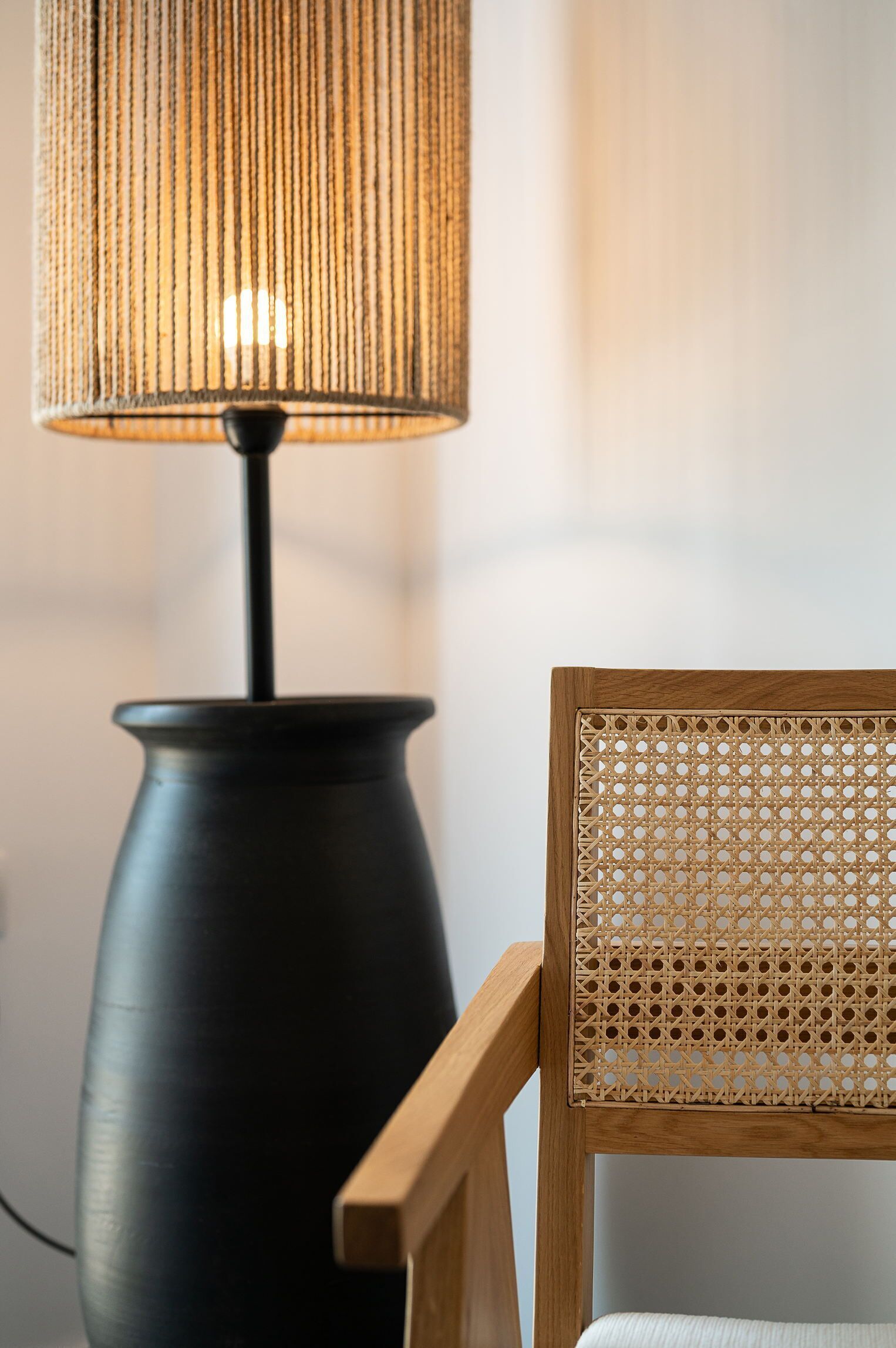 En lampe med rillet skærm og en træstol med flettet ryg.