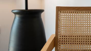 En lampe med rillet skærm og en træstol med flettet ryg.