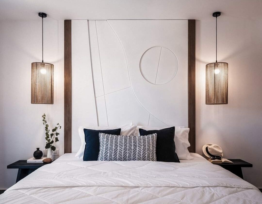 A modern bedroom with a large bed, two bedside tables, and a unique wall design.