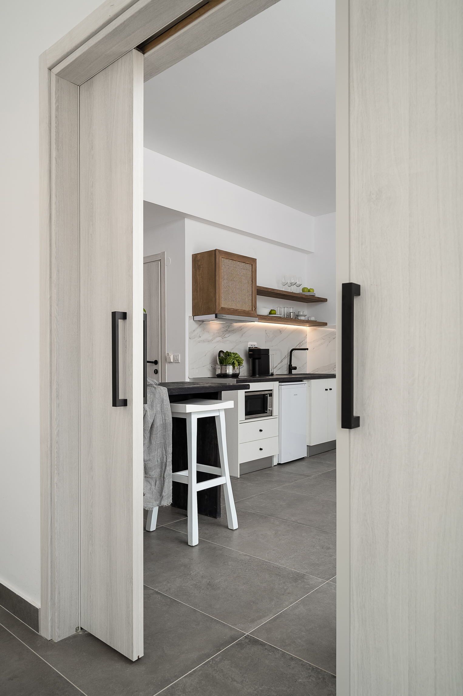 A modern kitchen with white cabinets, a black countertop, and a wooden ceiling.