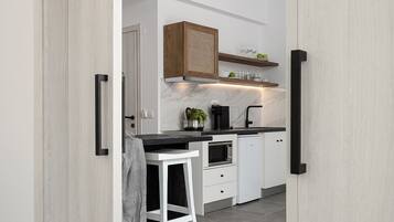 A modern kitchen with white cabinets, a black countertop, and a wooden ceiling.