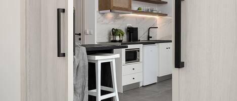 Una cocina moderna con armarios blancos, encimera negra y techo de madera.