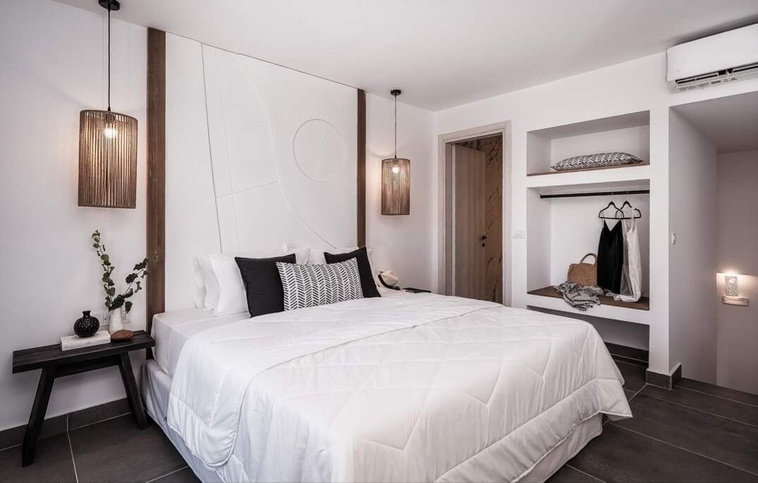 A modern bedroom with a large bed, bedside tables, a wardrobe, and a hanging light fixture.