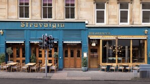 Un bâtiment à la façade bleue, sur lequel on peut lire l’inscription « Stravaigin ». Devant le bâtiment, on trouve des tables et des chaises en plein air.