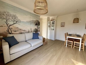 En stue med en sofa, et spisebord med stole, et billede på væggen og en fletlampe i loftet.
