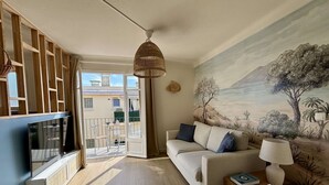 Una sala de estar con un sofá, un televisor, una lámpara y un cuadro en la pared.