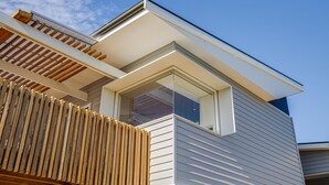 Un bâtiment moderne doté d’un toit en pente, de grandes fenêtres et d’une clôture en bois.
