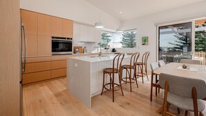 Une cuisine moderne avec des meubles en bois, un îlot central et un coin repas comprenant des chaises et une table en bois.