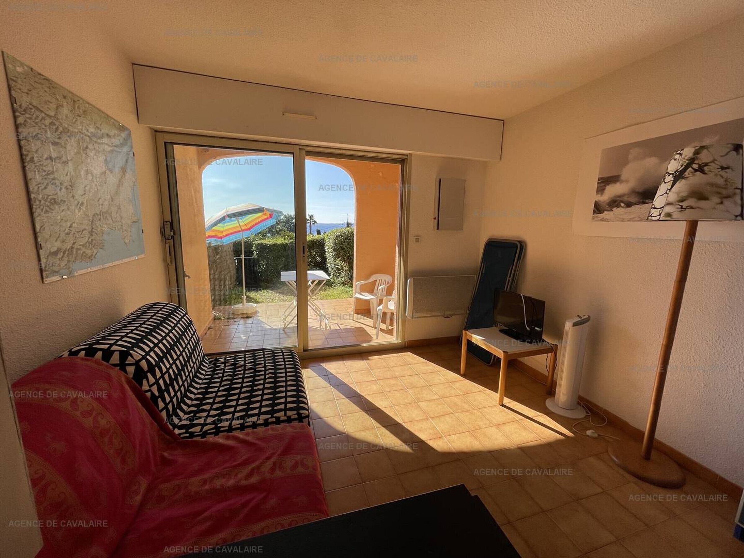 Una habitación con sofá, televisión y puerta corrediza de vidrio que da a un espacio exterior con mesa y sillas.