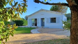 A single-story white building with a gravel driveway and a lawn. - Maison de Vacances à 15 Km de Saint-jean de Mont (Sallertaine)