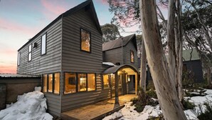 A two-story house with a wooden exterior, large windows, and a porch area. - Alpine Uralla - Dinner Plain (Dinner Plain)