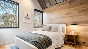 A modern bedroom with a large bed, a nightstand, a lamp, and framed artwork on the wall. - Alpine Uralla - Dinner Plain (Dinner Plain)