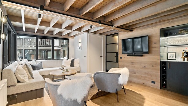 A modern living room with a wooden ceiling, a sofa, a coffee table, and a television mounted on the wall. - Alpine Uralla - Dinner Plain (Dinner Plain)