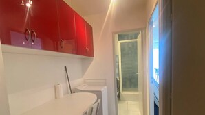 Una cocina compacta con encimeras blancas y armarios rojos.