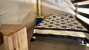 Una habitación con una cama, una mesita de noche de madera, una lámpara y una ventana con vistas al cielo.