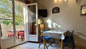 Habitación con puerta de vidrio corredera que da a un espacio exterior, una mesa con sillas, un televisor de pantalla plana montado en la pared y un letrero que indica que la habitación es para "OCEANS" con énfasis en "CHARROILED SEA FOOD".